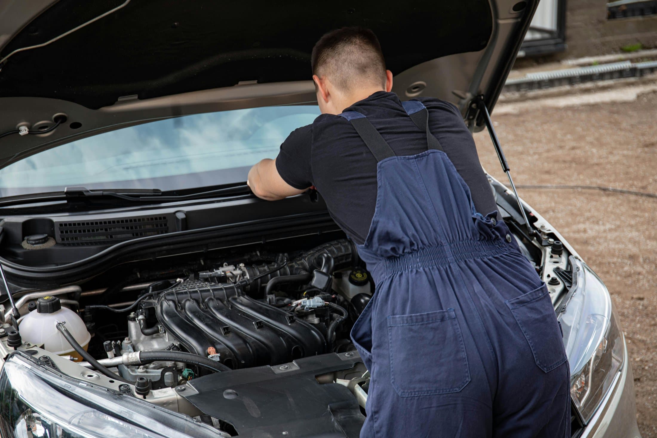 Mobile mechanic working under the hood of a vehicle